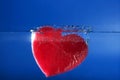 Candy red heart shape sinking into the blue water Royalty Free Stock Photo