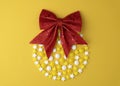 Candy in shape christmas toy ball with red bow, top view flat lay on yellow pastel background. Royalty Free Stock Photo