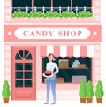 Candy shop, woman seller holding chocolate cake, sstanding at entrance to pastry shop