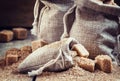 Cane brown sugar cubes and crystals in burlap sacks on old wooden background in rustic style, selective focus Royalty Free Stock Photo