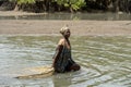 Unidentified local woman pulls a fishing net in the water in a