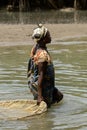 Unidentified local woman pulls a fishing net in the water in a