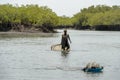 Unidentified local woman pulls a fishing net in the water in a