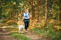 Canicross cross country running with dog, female musher running with Samoyed dog, sled dog racing