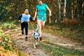 Canicross exercises, mother and her son running attached to Dalmatian dog, family outdoor activity