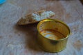 A canned can with red food residues and a piece of bread with a hard crust and a dusting in the form of pellets of grain