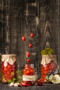 Canned cherry tomatoes fall into a jar on a wooden background with space for text Royalty Free Stock Photo