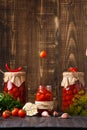 Canned cherry tomatoes fall into a jar on a wooden background with space for text Royalty Free Stock Photo