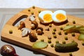 Canned green peas in a black plate, pickled mushrooms, appetizing pickled cucumbers and chicken boiled eggs.