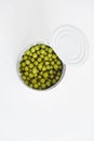 Canned green sweet peas in an open aluminum metal can on a white table. Top view. Copy  empty space for text Royalty Free Stock Photo