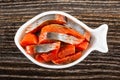 Canned herring - imitation salmon in bowl in shape fish on wooden table. Top view