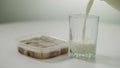 Canned herring on table with white milk pouring in glass. Close-up incompatible food and drink indoors.