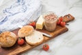 Canned liver sausage spread from long term pantry with crispy bread roll bun, butter, tomatoes and knife for snack or breakfast on