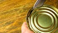 Canned meat. Human hands open canned stew in tin can, by dint of kitchen knife on a wooden table. Selective focus, copy space Royalty Free Stock Photo