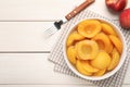 Canned peach halves and fork on white wooden table, flat lay. Space for text Royalty Free Stock Photo