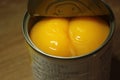 Canned peaches halves sprinkled with syrup in a metallic can on wooden floor Royalty Free Stock Photo