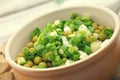 Canned peas with chives in ceramic bowl on wooden background. He