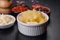 Canned pineapple chunks in a white bowl on a dark concrete background