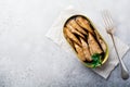 Canned sprats in tin can with fork on gray old concrete or stone background. Selective focus. Rustic style. Top view. Copy space Royalty Free Stock Photo