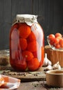 Canned tomatoes in glass jar on wooden rustic table in pantry or village kitchen, closeup, cottagecore, simple living aesthetics Royalty Free Stock Photo