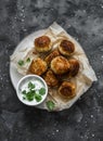 Canned tuna potato fish balls with greek yogurt cilantro sauce on dark background, top view