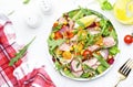 Canned Tuna salad with colorful cherry tomatoes, red onion, sweet corn, paprika, lettuce, radicchio and arugula. White table