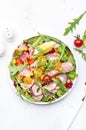 Canned Tuna salad with colorful cherry tomatoes, red onion, sweet corn, paprika, lettuce, radicchio and arugula. White table