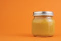 Canned vegetable or fruit puree in a glass jar on an orange background. The concept of baby food, canned food, orange vegetables Royalty Free Stock Photo