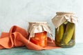 Canned vegetables in glass jars and a linen napkin on a green background.