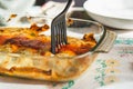 Cannelloni with spinach close up, tomato sauce, bachamel and cheese on table cloth with fork taking portion . Traditional homemade Royalty Free Stock Photo