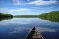canoe on glassy lake, with tranquil reflections and serene blue skies