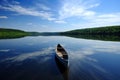 canoe on glassy lake, with tranquil reflections and serene blue skies