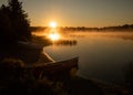 Canoe on the shore of a misty lake at sunrise/sunset. Royalty Free Stock Photo