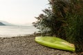 Canoe stranded upside down on rocks by lake and reeds Royalty Free Stock Photo