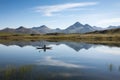 canoeist paddling along a tranquil lake, with mountains in the background Royalty Free Stock Photo