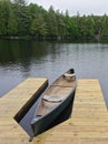 Canoes tied to a wooden dock on a lake surrounded by evergreen trees Royalty Free Stock Photo