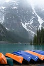 Canoes in turquoise Lake Louise with misty mountains in the background