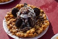 A funnel cake with chocolate drizzle, whipped cream, oreo cookies and powdered sugar sits on display at a Farmer`s Market.