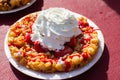 A funnel cake with strawberry drizzle, whipped cream and powdered sugar sits on display at the Canoga Park Farmer`s Market.