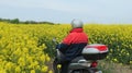 Canola blossom in spring in Schleswig-Holstein, Germany, A man carefully drives a scooter through a flowering rapeseed field on a