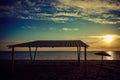 Canopy and old metal umbrella on an empty sandy beach at sunset Royalty Free Stock Photo