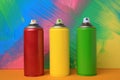 Cans of different spray paints on color background. Graffiti supplies Royalty Free Stock Photo
