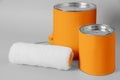 Cans of orange paint and roller brush on grey background Royalty Free Stock Photo