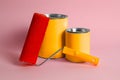 Cans of orange paint and roller on pink background Royalty Free Stock Photo