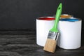 Cans of paint and brush on black wooden table Royalty Free Stock Photo