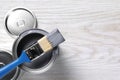 Cans of paints and brush on white wooden table, flat lay. Space for text Royalty Free Stock Photo