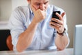 This cant be good...a tired-looking businessman reading an sms while sitting in front of his laptop. Royalty Free Stock Photo