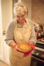 Cant wait to dig in. An elderly lady holding a pie that shes just baked.