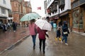 Shoppers dress for the heavy rain and carry umbrellas on the pedestrian parade
