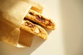 Cantucci cookies with candied fruits and nuts in a paper bag. White background, sunlight Royalty Free Stock Photo